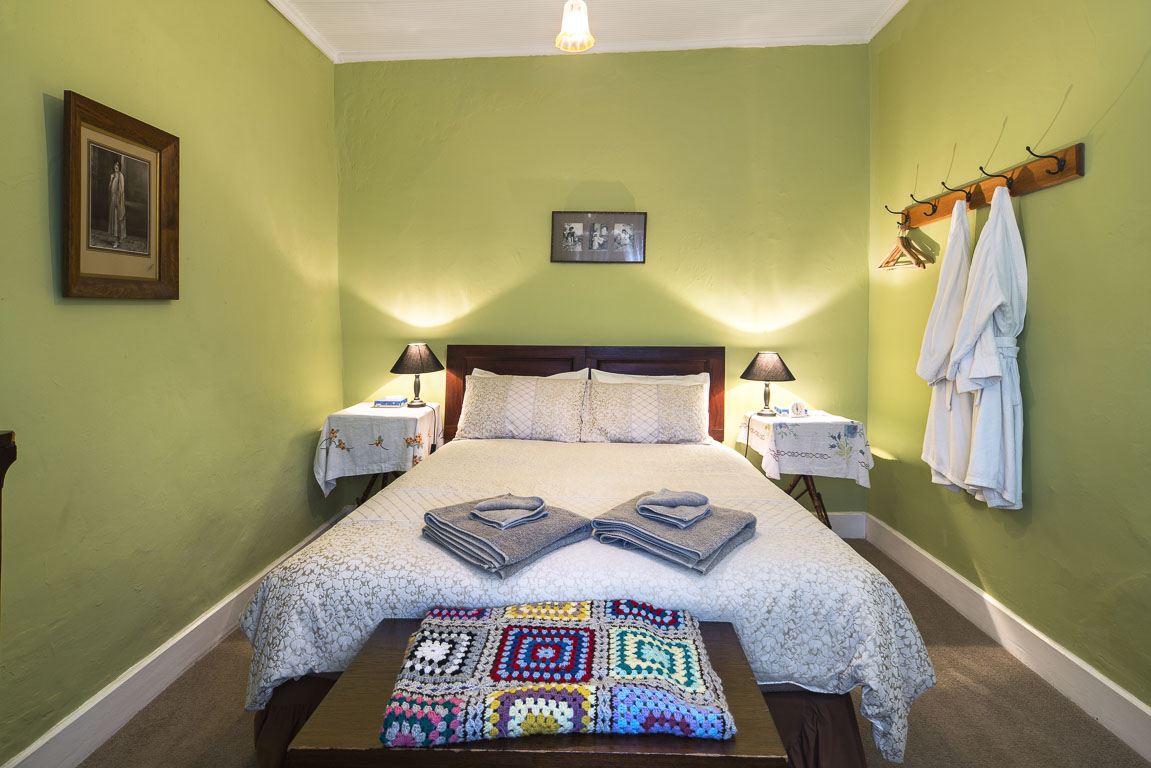 Cottage 8's queen bedroom with folded towels and bathrobes hanging by the door