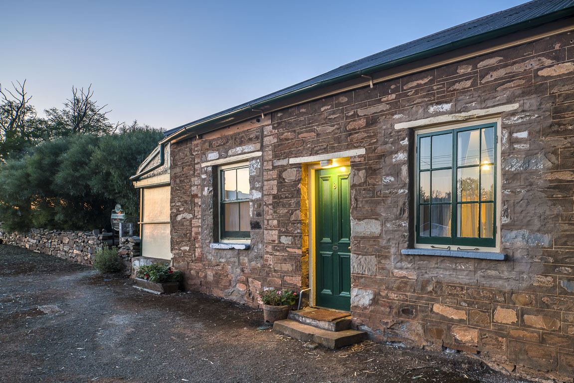 Cottage 8 at dusk, stone walls and a lit green front door